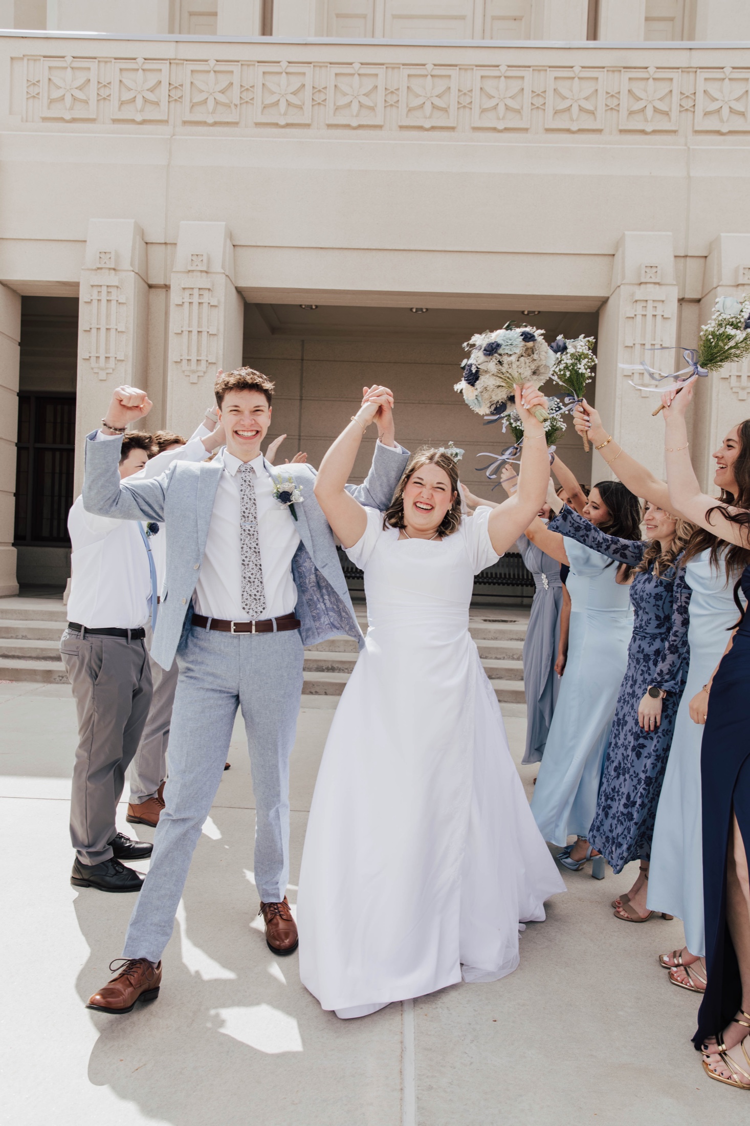Bride and groom cheering, surrounded by their wedding party
