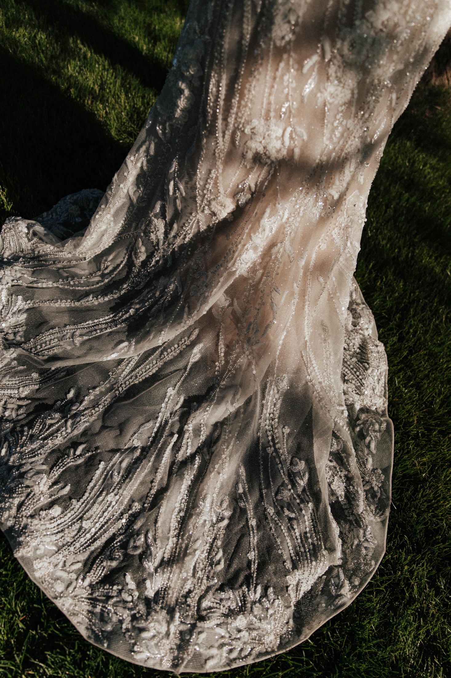 Beaded gown train fanned across the grass