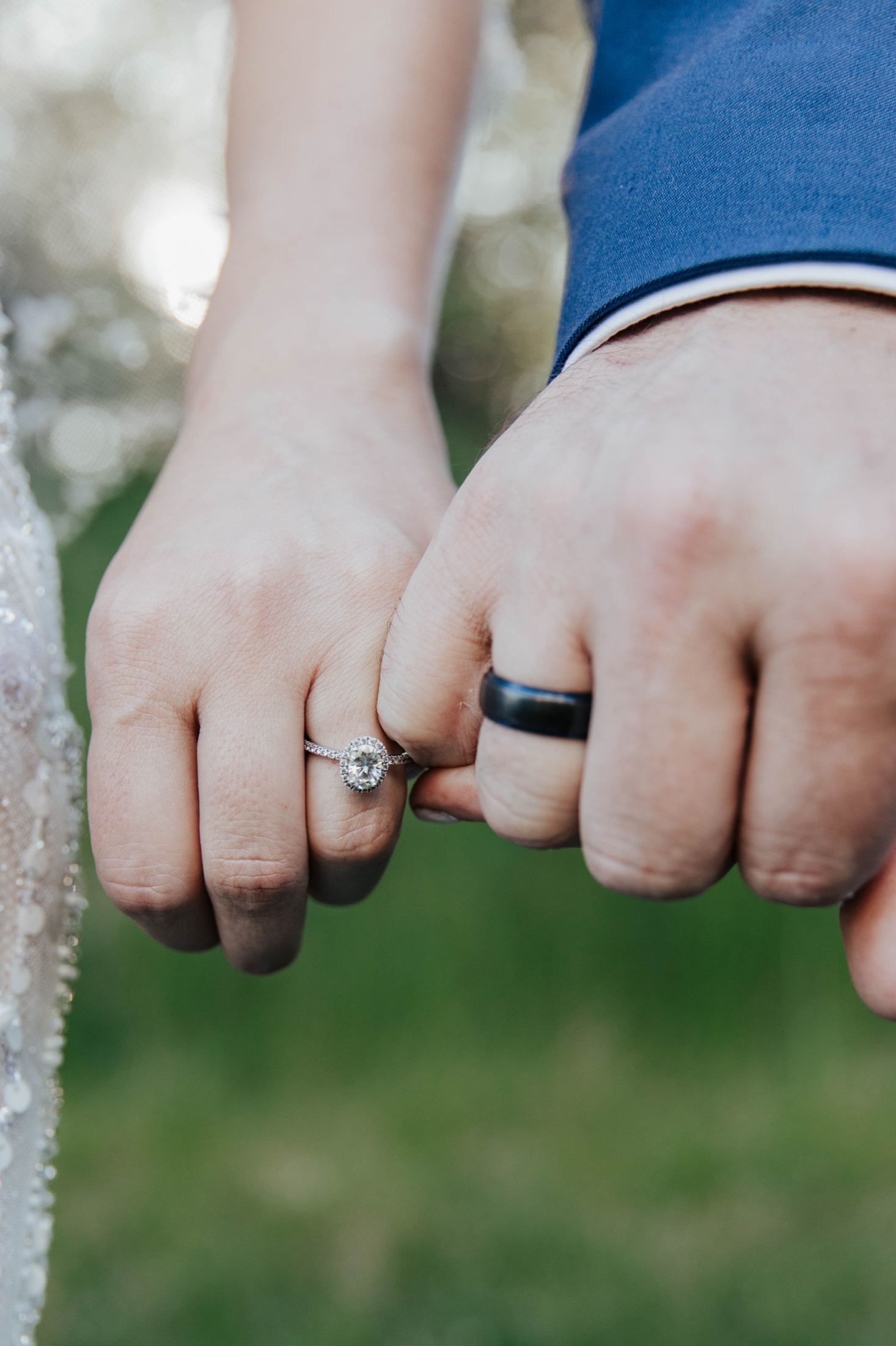 Bride and groom linking pinkies, rings showing