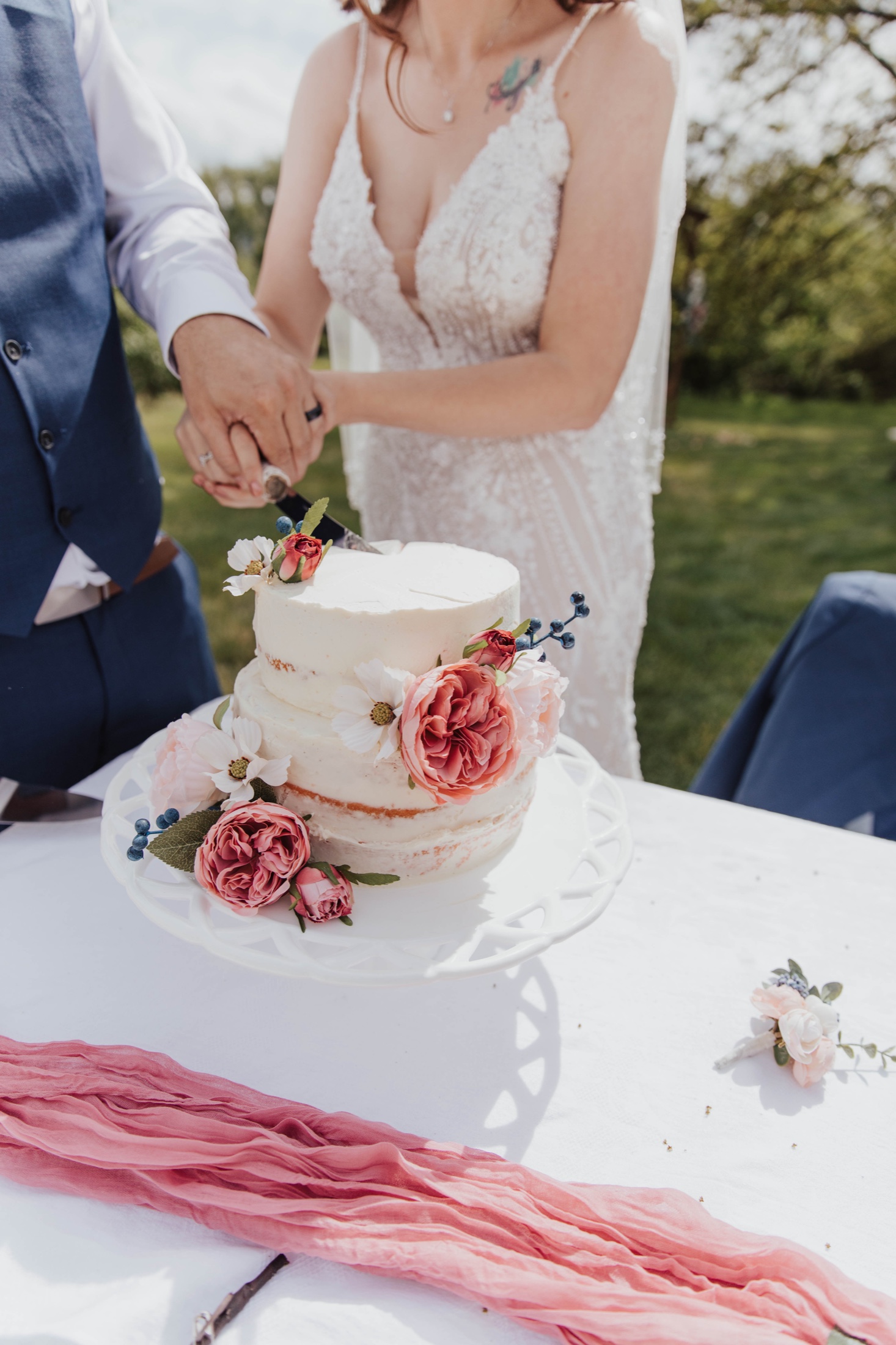 Cutting a flower-covered cake outdoors