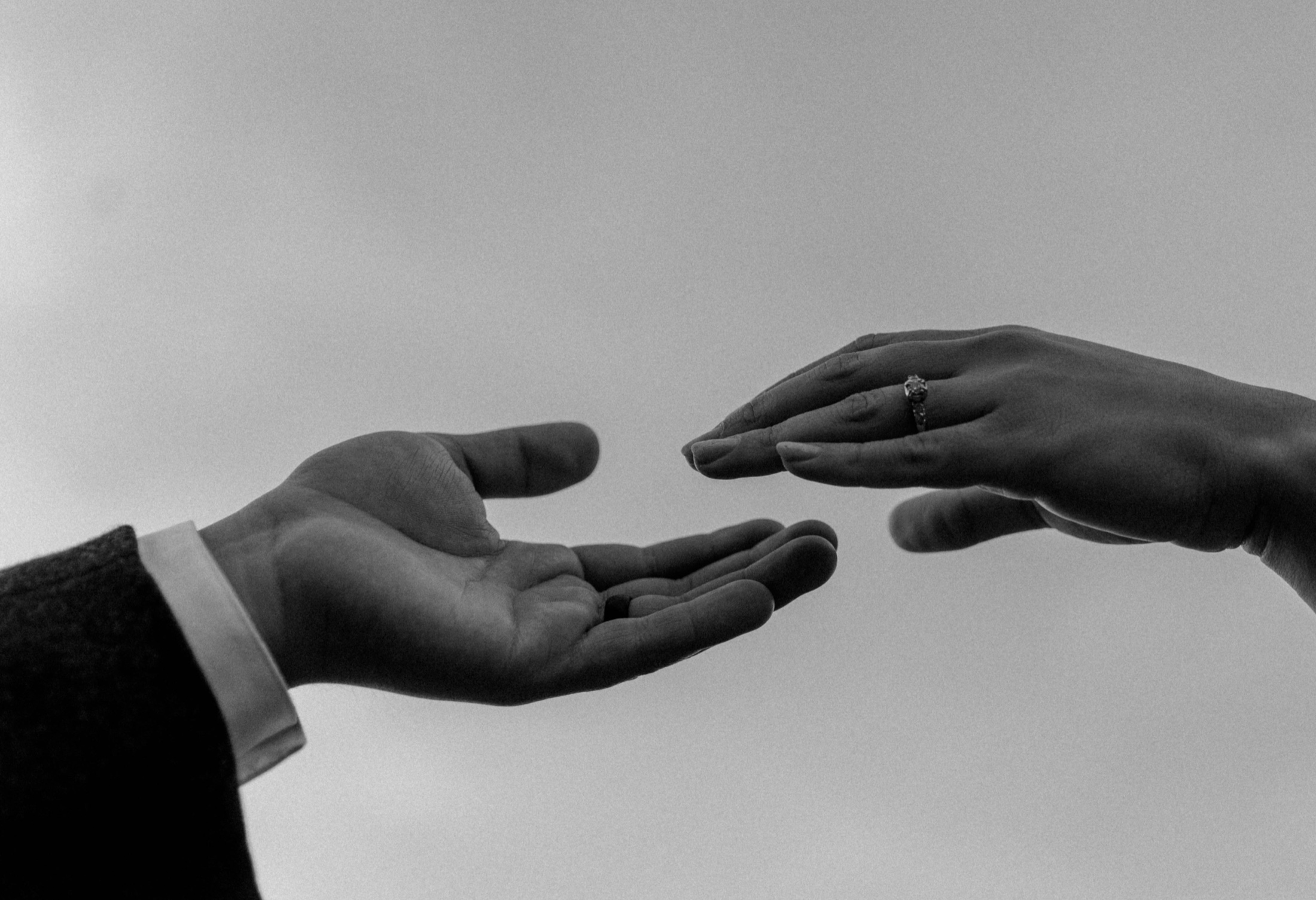 Two hands reaching toward each other in black and white